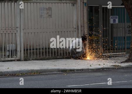 Salvador, Bahia, Brasilien - 25. Januar 2024: Schmied sieht Eisen mit einer Scheibenmaschine auf dem Boden der Avenida 7 de Setembro in Salvador, Bah Stockfoto