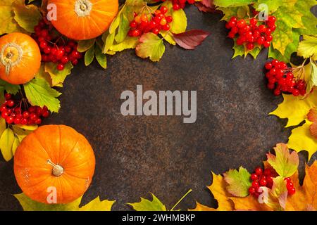 Saisonaler Hintergrund. Herbstkomposition mit herbstlichen Ahornblättern, Kürbis, Nüssen und Beeren auf Schieferhintergrund. Draufsicht flach Stockfoto