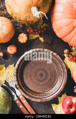 Thanksgiving-Tag-Konzept. Herbsttisch für Abendessen mit Teller, Messer, gabelverzierten Kürbissen und Ahornblättern. Flache Lagen Stockfoto