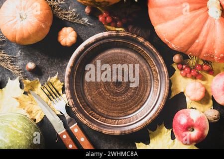 Thanksgiving-Tag-Konzept. Herbsttisch für Abendessen mit Teller, Messer, gabelverzierten Kürbissen und Ahornblättern. Flache Lagen Stockfoto