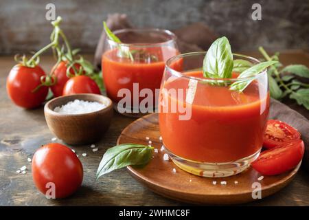 Gläser frischer Tomatensaft mit Tomaten, Salz auf einem Holztisch. Gemüse-Tomaten-Getränk für eine gesunde Ernährung. Stockfoto