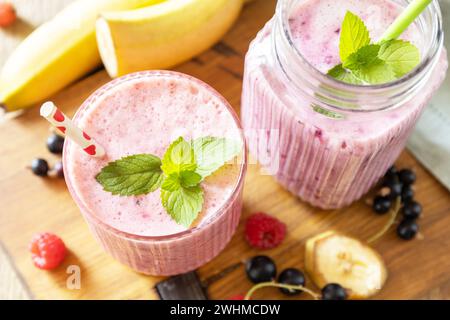 Set aus frischen, verschiedenen köstlichen Milchshakes oder Smoothies mit frischen Beeren auf rustikalem Hintergrund. Himbeeren und schwarze Johannisbeere. Stockfoto