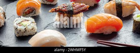 Sushi-Panorama. Brötchen, Nigiri auf schwarzem Hintergrund, japanisches Essen Stockfoto