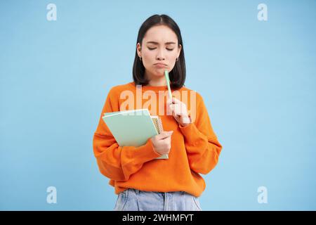 Bildung und Studenten. Glückliche asiatische Frau, die Notizbücher hält und lacht, in die Kamera lächelt, genießt es, zur Universität oder zum Coll zu gehen Stockfoto