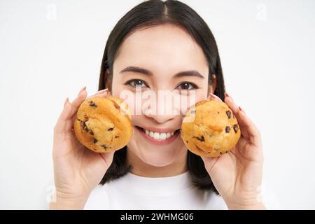 Foto einer fröhlichen, reizenden, süßen Frau mit bob-Haaren-verkleidete Finger halten Cupcake isoliert auf weißem Hintergrund Stockfoto