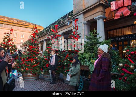 Weihnachtsbäume und festliche Shopper im Luxury District von London. Stockfoto