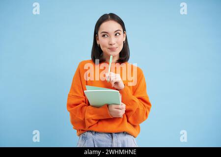 Bildung und Studenten. Glückliche asiatische Frau, die Notizbücher hält und lacht, in die Kamera lächelt, genießt es, zur Universität oder zum Coll zu gehen Stockfoto