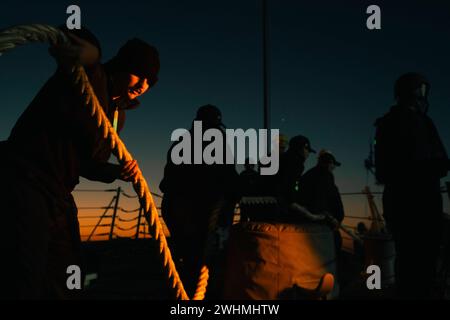 240202-N-EJ843-1017 ROTA, Spanien (2. Februar 2024) – Seeleute an Bord der Arleigh-Burke-Klasse USS Delbert D. Black (DDG 119) steuern die Linie, während das Schiff am 2. Februar 2024 von der Marinestation Rota, Spanien, verlässt. Delbert D. Black befindet sich auf einem geplanten Einsatz im Gebiet der U.S. Naval Forces Europe und wird von der U.S. Sixth Fleet eingesetzt, um die Interessen der USA, der Alliierten und der Partner zu verteidigen. (Foto der US Navy von Mass Communication Specialist 2nd Class Jimmy Ivy III) Stockfoto