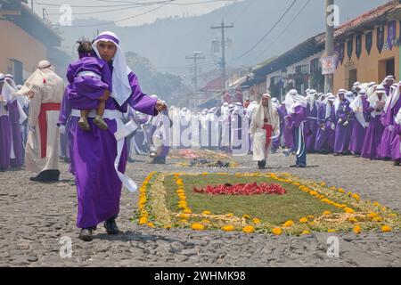 Antigua, Guatemala. Weihrauch erfüllt die Luft, während Cucuruchos in violetten Tuniken den Weg für eine religiöse Prozession während der Karwoche La Semana Santa bereiten. Stockfoto