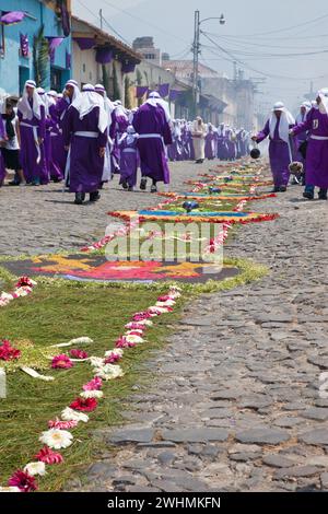 Antigua, Guatemala. Weihrauch erfüllt die Luft, während Cucuruchos in violetten Tuniken den Weg für eine religiöse Prozession während der Karwoche La Semana Santa bereiten. Stockfoto