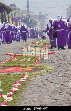 Antigua, Guatemala. Weihrauch erfüllt die Luft, während Cucuruchos in violetten Tuniken den Weg für eine religiöse Prozession während der Karwoche La Semana Santa bereiten. Stockfoto