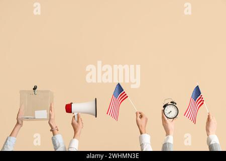 Zeiger mit Stimmzettel, USA-Flaggen, Megaphon und Wecker auf beigefarbenem Hintergrund. Wahlkonzept Stockfoto
