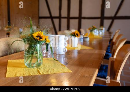 Lange Holztische, dekoriert mit Blumensträußen und Kaffeetassen für ein Treffen oder informelles Treffen eines Vereins i Stockfoto