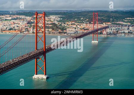 Hochwinkelblick auf die Brücke vom 25. April in Lissabon, bewölkter Himmel aus rotem Stahl, über dem Meer. Stockfoto