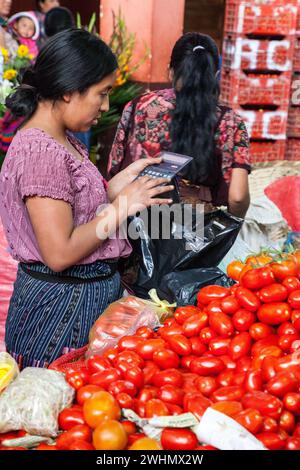 Chichicastenango, Guatemala.  Tomaten Berechnung Händlerpreis eines Verkaufs in der Markthalle.  Quiche (k ' iche ') ethnische Gruppe. Stockfoto