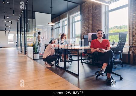 In einem modernen Startup Coworking Center arbeitet eine vielfältige Gruppe von Geschäftsleuten zusammen, die eine Mischung aus papierbasiertem und verwenden Stockfoto