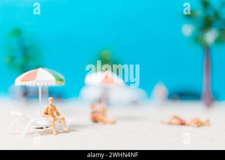 Miniaturgänger in Badeanzügen, die sich am Strand entspannen Stockfoto