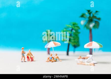 Miniaturgänger in Badeanzügen, die sich am Strand entspannen Stockfoto