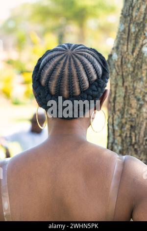 Afrikanische Frisur, Frau mit Zöpfen, die draußen im Garten mit dem Rücken steht Stockfoto