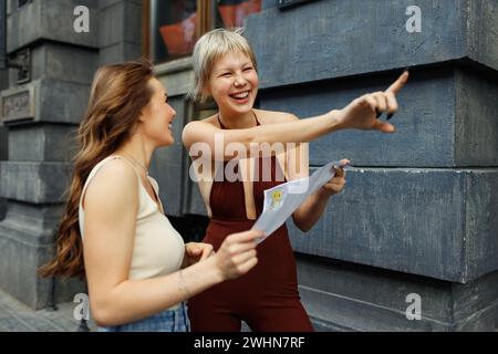 Glückliche junge Touristen-Reisende mit Papierkarte erkunden die neue Stadt. Stockfoto