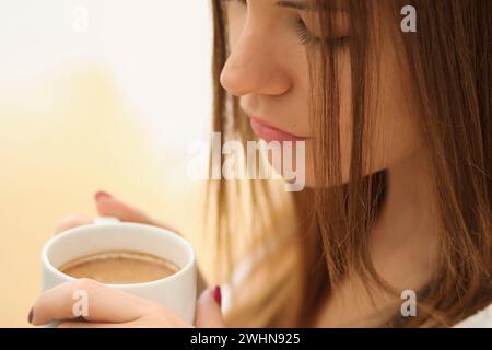 Mujer joven bebiendo de una taza Stockfoto