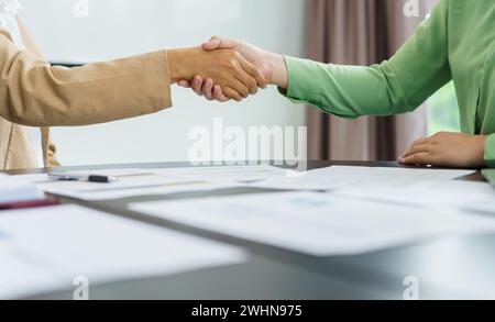 Geschäftsleute schütteln bei erfolgreicher Geschäftsbesprechung im Vorstandssitz die Hand mit einem nicht erkennbaren Kollegen. Stockfoto