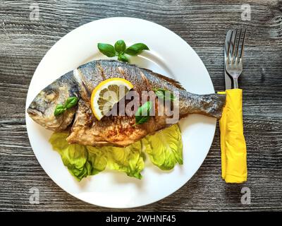 Gebratener Fisch mit Goldbrasse auf dem Teller mit Gemüse, Draufsicht Stockfoto