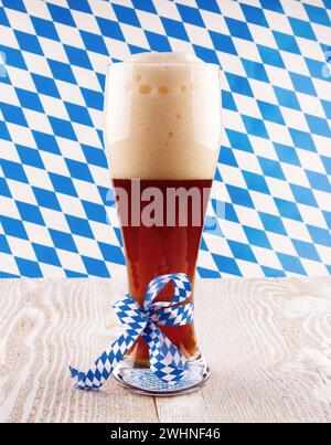 Dunkles Weizenbier in Glas auf bayerischem Hintergrund Stockfoto