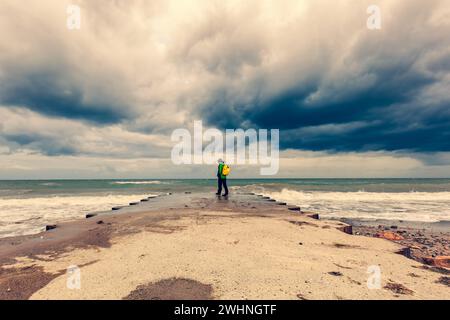 Reisende am Strand in der Nähe des Meeres mit Blick weit weg am Horizont, wilde Brandung mit Wellen. Ostsee Stockfoto