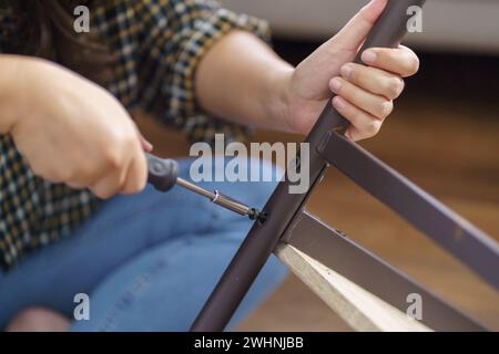 Asiatische Frau repariert Möbel-Renovierung selbst, indem sie Ausrüstung zum selbermachen von Möbeln verwendet, die zu Hause auf dem Boden sitzen Stockfoto