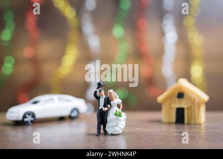 Miniaturmenschen Braut und Bräutigam auf Holzboden mit farbenfrohem Bokeh Hintergrund Stockfoto