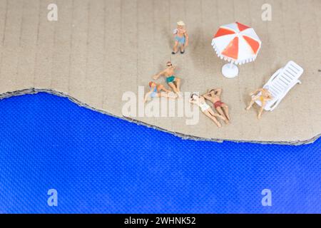 Miniaturgänger in Badeanzügen, die sich am Strand entspannen Stockfoto