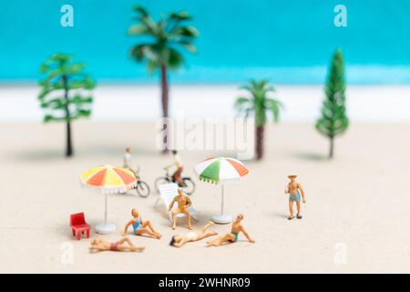 Miniaturgänger in Badeanzügen, die sich am Strand entspannen Stockfoto