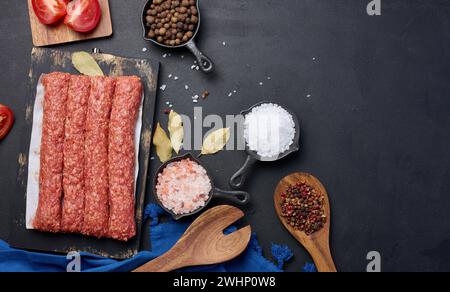 Rohe lula Kebab-Würstchen auf einem Brett und Gewürze, Blick von oben Stockfoto