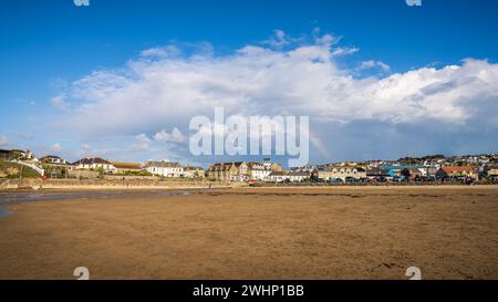 Perranporth, Cornwall, England, Großbritannien - 5. Juni 2022: Häuser in der Nähe von Perranporth Beach mit einem Regenbogen im Hintergrund Stockfoto