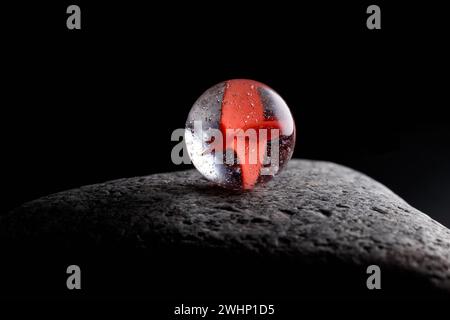 Eine transparente Glaskugel mit Luftblasen und ein Design auf grauen Kieseln. Nahaufnahme. Abstraktion. Stockfoto
