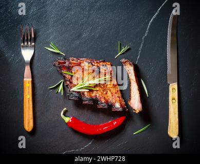 Gegrillte Spareribs auf Schieferteller mit Besteck Stockfoto
