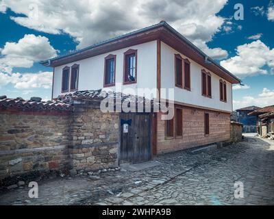 Knysna, Bulgarien - engen, gepflasterten Straßen und rustikalen traditionelle Häuser aus Stein und Holz mit bigroot cranesbill (Geranium macrorrhizum) zusammen. Stockfoto