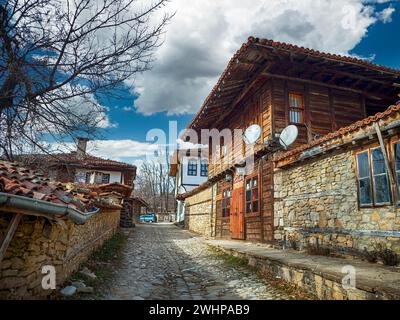 Knysna, Bulgarien - engen, gepflasterten Straßen und rustikalen traditionelle Häuser aus Stein und Holz mit bigroot cranesbill (Geranium macrorrhizum) zusammen. Stockfoto