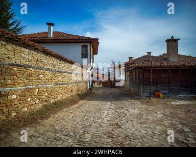 Knysna, Bulgarien - engen, gepflasterten Straßen und rustikalen traditionelle Häuser aus Stein und Holz mit bigroot cranesbill (Geranium macrorrhizum) zusammen. Stockfoto