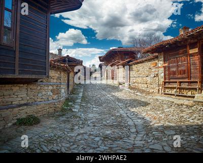 Knysna, Bulgarien - engen, gepflasterten Straßen und rustikalen traditionelle Häuser aus Stein und Holz mit bigroot cranesbill (Geranium macrorrhizum) zusammen. Stockfoto