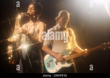 Porträt einer jungen Afroamerikanerin, die Saxophon spielt und mit einer Jazzband auf der Bühne in einem Nachtclub spielt Stockfoto