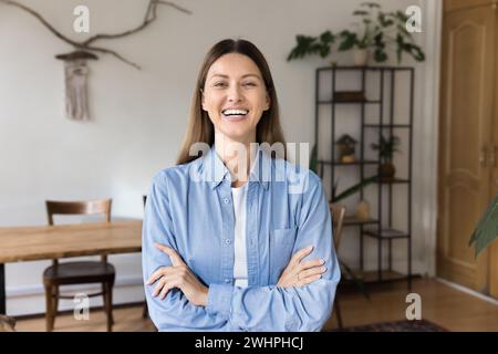 Glückliche, selbstbewusste, schöne Unternehmerin posiert mit gefalteten Armen Stockfoto