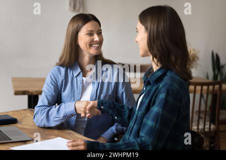 Zwei fröhliche junge Startup-Partner schütteln die Hand und beenden die Verhandlungen Stockfoto