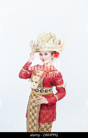 Weibliches Modell mit Lampung-Geschwisterkrone oder traditioneller Lampung-Kleidung mit goldenen Accessoires und rotem Kleid, isoliert auf weiß Stockfoto