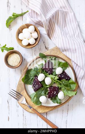 Gesunder Diät-Salat mit Rucola, Spinat, Rote Bete, Mozzarella und Vinaigrette Dressing auf einem Holztisch. Kalorienarme Keto sterben Stockfoto