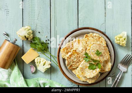 Blumenkohlgemüse mit Käse auf einem rustikalen Küchentisch. Gebratene vegetarische Schnitzel oder Pfannkuchen. Blick von oben. Cop Stockfoto
