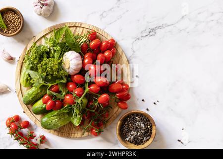 Hauswirtschaftslehre, Herbsternterhaltung. Frische Tomaten, Gurken und Gewürze für gesunde hausgemachte Gärung auf einer Marmorplatte Stockfoto