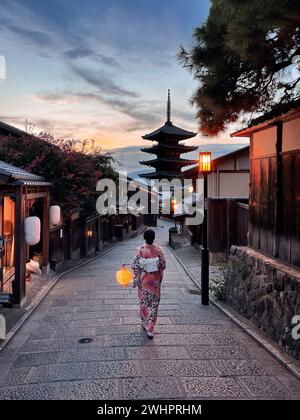 Asiatische Reisende, die traditionelle japanische Kimonos tragen und eine Laterne halten, spazieren durch den Bezirk Higashiyama bei Sonnenuntergang am 29. August 2022 in Kyoto, Japan. Higashiyama-ku bewahrt das Aussehen und die Atmosphäre des Feudalzeitalters Japans in einem holzgebauten historischen Viertel mit engen Gassen, gesäumt von traditionellen Töpfereien, Teehäusern und Restaurants. Foto von Victor Fraile / Power Sport Images Stockfoto