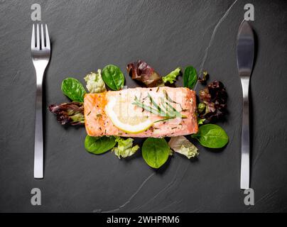 Gegrilltes Lachsfilet mit Salat auf schwarzem Schiefer Platte Stockfoto